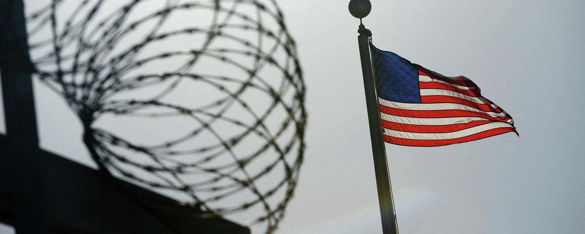 Uma bandeira dos EUA tremula acima de uma cerca de arame farpado no centro de detenção Camp Six (acampamento seis) na Estação Naval dos EUA na Baía de Guantánamo, 10 de dezembro de 2008 - Sputnik Brasil, 1920, 15.03.2022