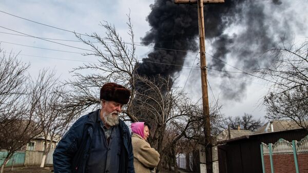 Em Lugansk, na República Popular de Lugansk (RPL), duas pessoas caminham, com uma coluna de fumaça ao fundo, em 7 de março de 2022. - Sputnik Brasil