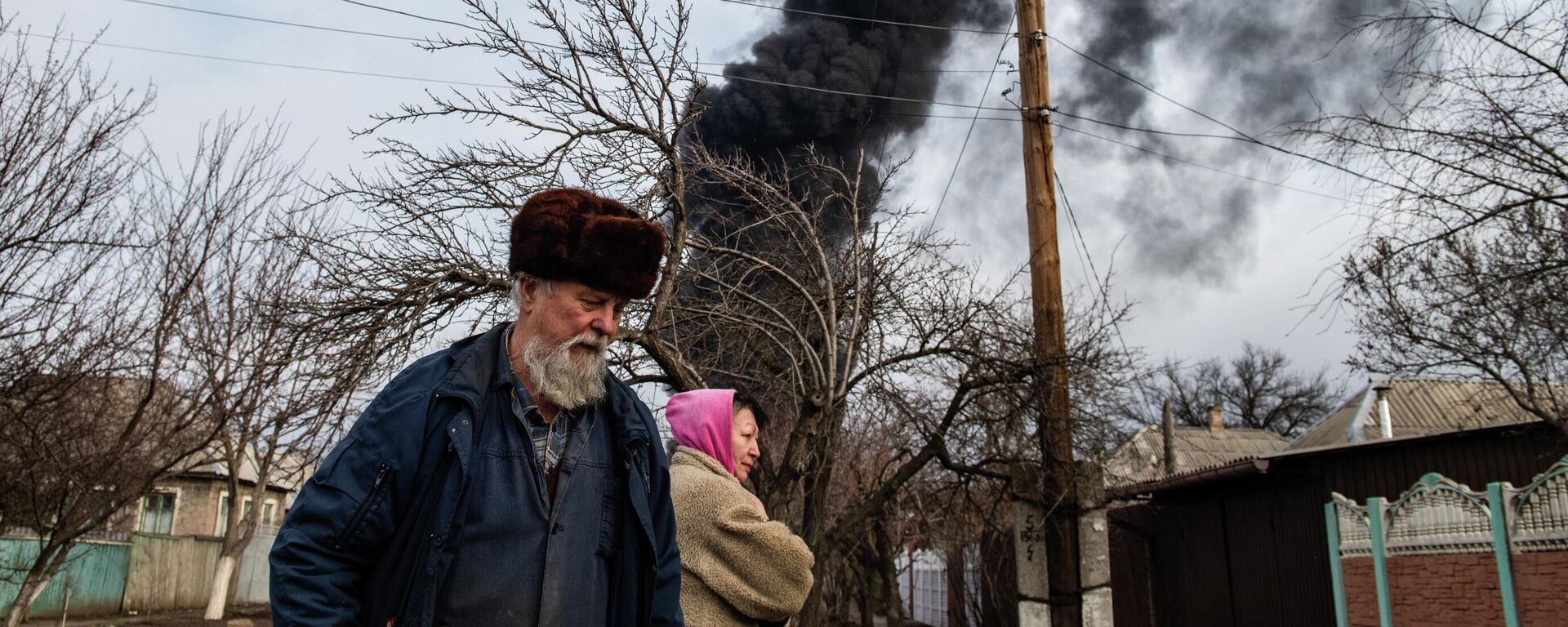 Em Lugansk, na República Popular de Lugansk (RPL), duas pessoas caminham com uma coluna de fumaça ao fundo, em 7 de março de 2022 - Sputnik Brasil, 1920, 30.03.2022