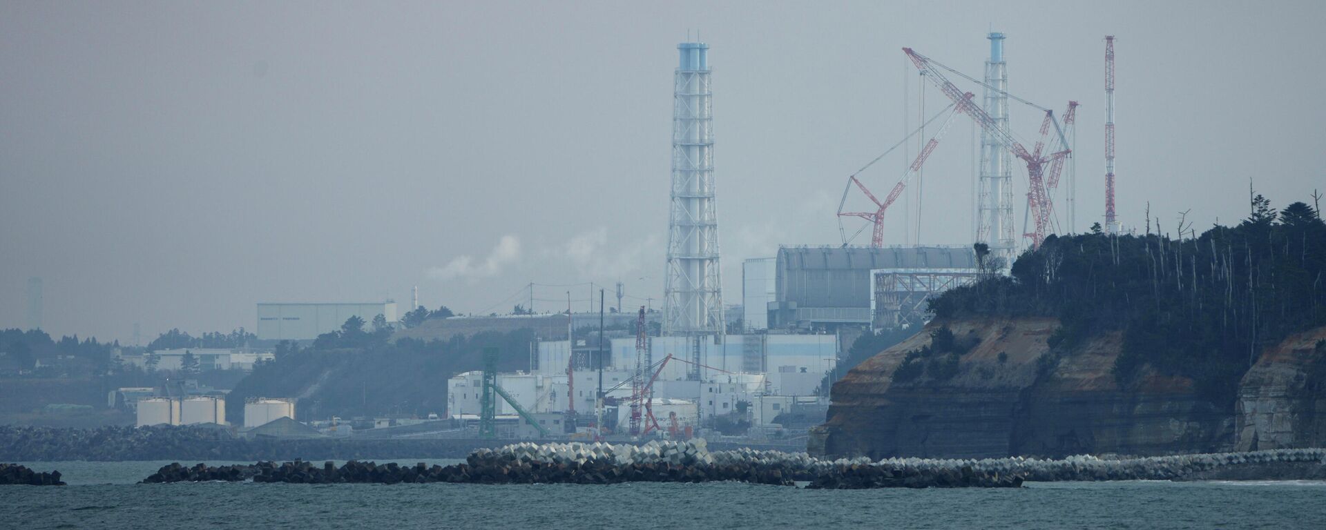 A usina nuclear de Fukushima Daiichi fica nas cidades costeiras de Okuma e Futaba, vista do porto de pesca de Ukedo na cidade de Namie, nordeste do Japão, quarta-feira, 2 de março de 2022 - Sputnik Brasil, 1920, 01.09.2023
