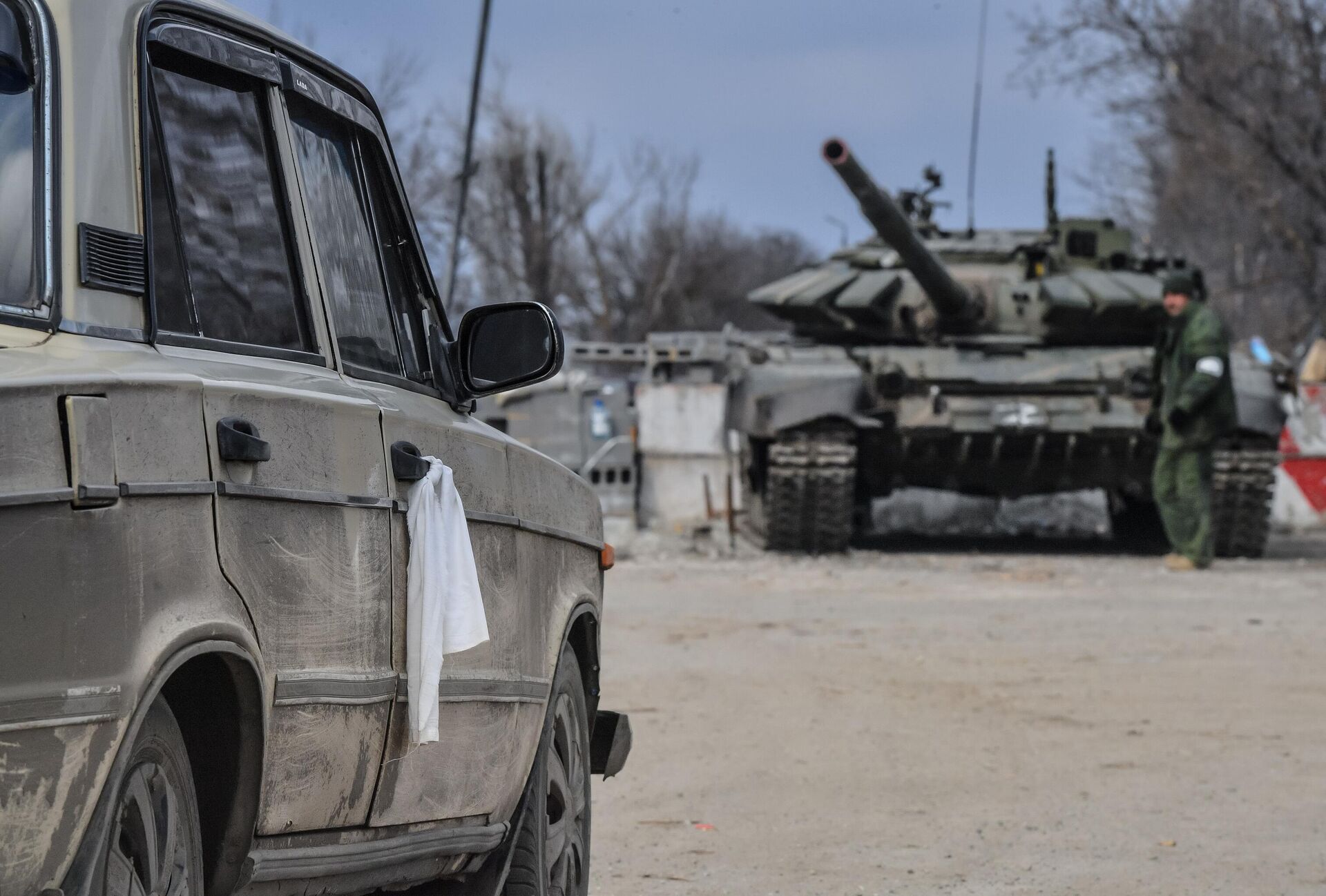 Em Mariupol, na República Popular de Donetsk (RPD), um carro com residentes locais é visto deixando a cidade com um tanque militar ao fundo, em 24 de fevereiro de 2022 - Sputnik Brasil, 1920, 21.03.2022