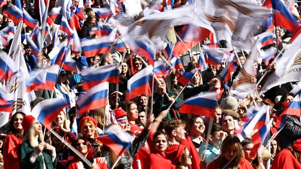 Pessoas agitam bandeiras russas durante concerto marcando oitavo aniversário da reintegração da Crimeia na Rússia no Estádio Luzhniki, Moscou, Rússia, 18 de março de 2022 - Sputnik Brasil