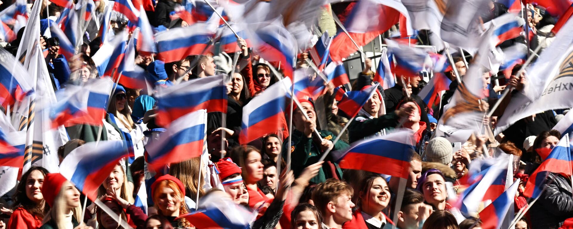 Pessoas agitam bandeiras russas durante concerto marcando oitavo aniversário da reintegração da Crimeia na Rússia no Estádio Luzhniki, Moscou, Rússia, 18 de março de 2022 - Sputnik Brasil, 1920, 25.03.2022