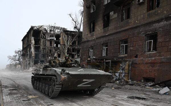 Carro de combate da infantaria BMP-1 das forças da República Popular de Donetsk junto de prédio residencial destruído em Mariupol - Sputnik Brasil
