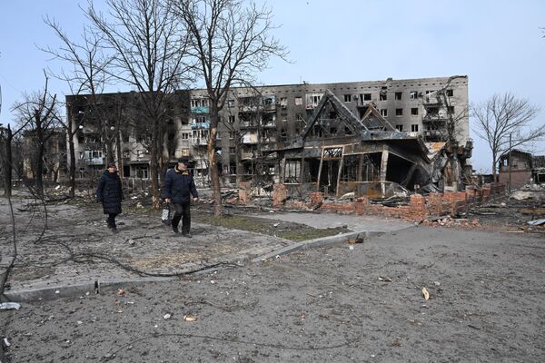 Moradores passam junto de prédios residenciais destruídos em Mariupol - Sputnik Brasil