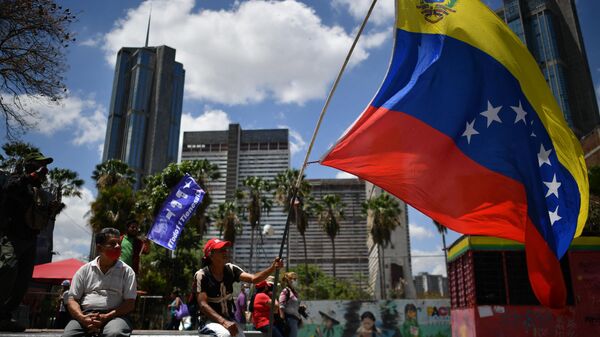 Apoiador do governo hasteia bandeira venezuelana em 20º aniversário durante aniversário de golpe de Estado que temporariamente removeu o então presidente Hugo Chávez em Caracas, Venezuela, 13 de abril de 2022 - Sputnik Brasil