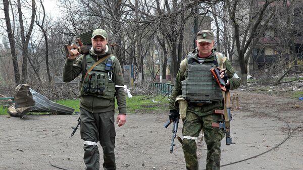Militares armados da Milícia Popular de Donetsk olham para um fotógrafo enquanto carregam armas capturadas em Mariupol, em 15 de abril de 2022 (foto de arquivo) - Sputnik Brasil
