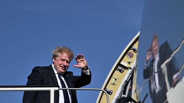 O primeiro-ministro britânico, Boris Johnson, acena ao embarcar em um avião no aeroporto de Stansted, nos arredores de Londres, para uma visita à Índia, 20 de abril de 2022 - Sputnik Brasil