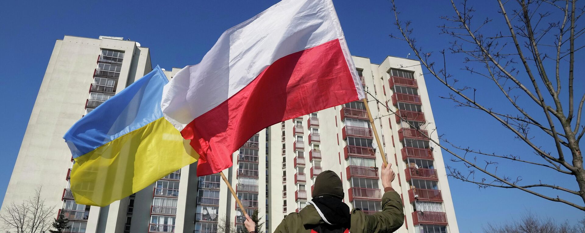 Um homem balança as bandeiras da Ucrânia e da Polônia durante manifestação em frente a um prédio em que estão hospedados diplomatas russos, em Varsóvia, na Polônia, 13 de março de 2022 - Sputnik Brasil, 1920, 02.06.2022