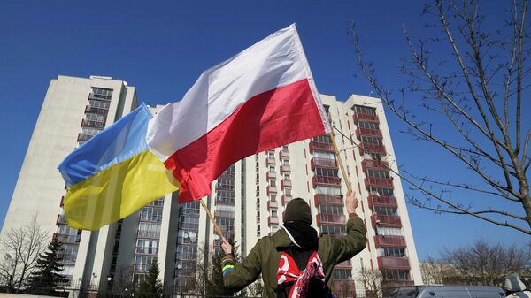 Um homem balança as bandeiras da Ucrânia e da Polônia durante manifestação em frente a um prédio em que estão hospedados diplomatas russos, em Varsóvia, na Polônia, 13 de março de 2022 - Sputnik Brasil