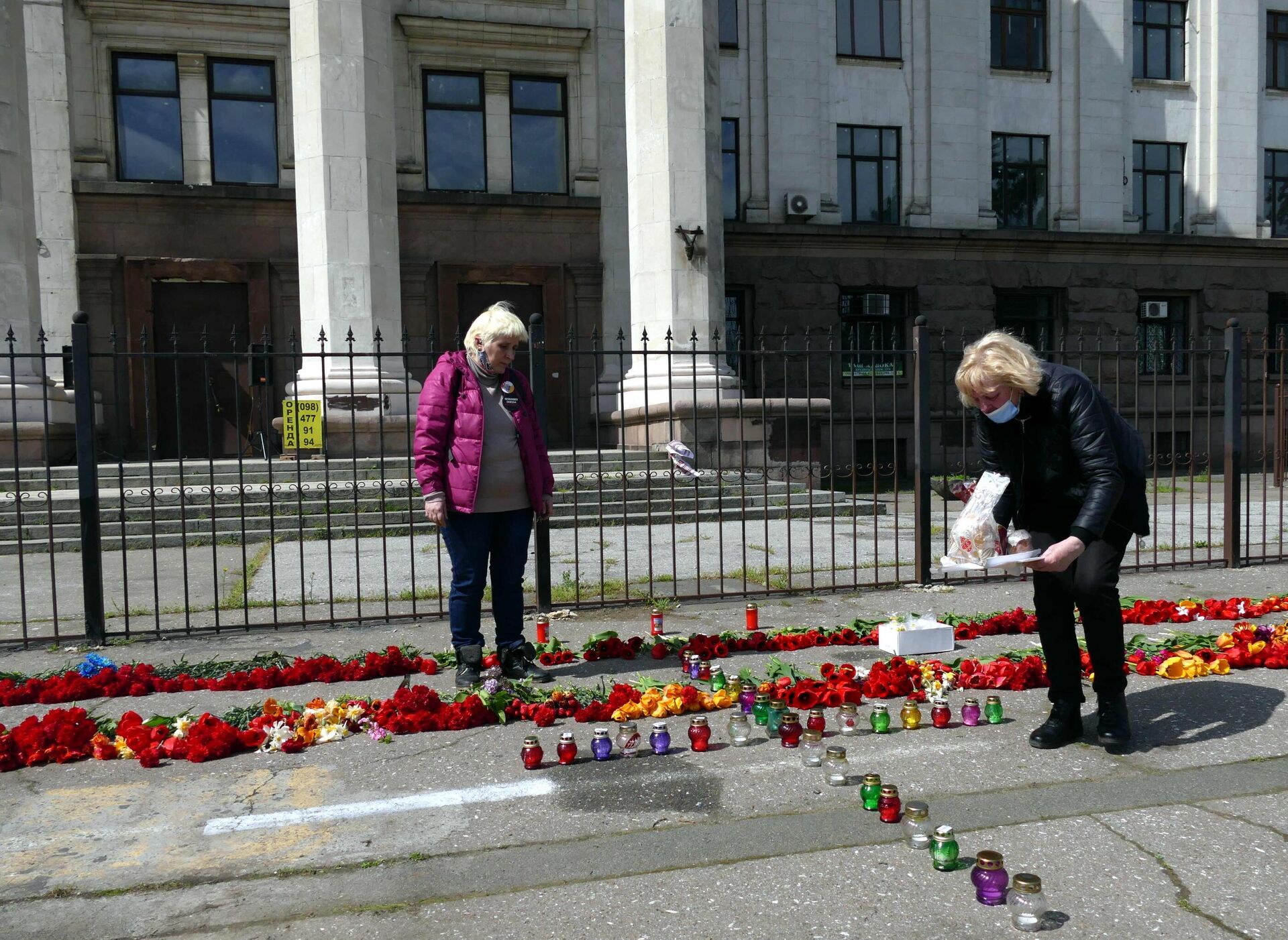 Moradores colocam cruz em forma de lâmpadas em ato comemorativo da memória das vítimas de ativistas anti-Maidan que morreram na Casa dos Sindicatos (no fundo) de Odessa, Ucrânia, 2 de maio de 2021 - Sputnik Brasil, 1920, 02.05.2023