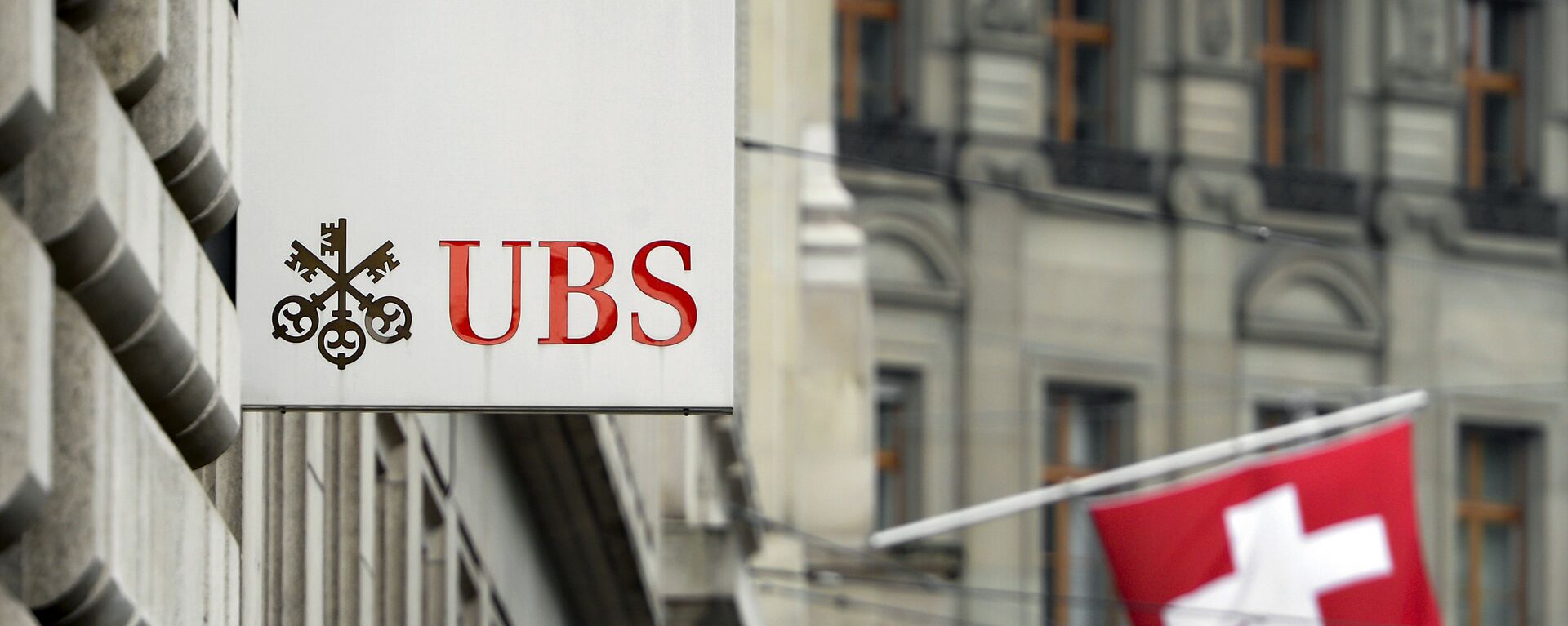 A bandeira suíça é vista atrás da logo do gigante bancário suíço UBS em Basileia, 11 de junho de 2013 - Sputnik Brasil, 1920, 14.05.2022