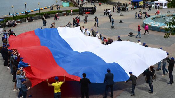 Pessoas seguram bandeira russa em Vladivostok, 12 de junho de 2018 - Sputnik Brasil