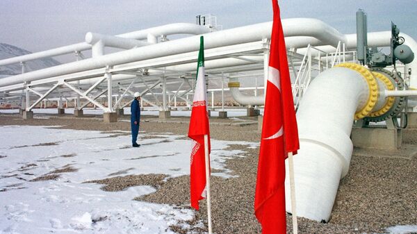 Trabalhador iraniano em frente a gasodutos ao lado das bandeiras da Turquia (D) e Irã após a inauguração de um gasoduto que entrega gás natural à Turquia, em Bazargan, na fronteira entre os dois países, 22 de janeiro de 2002 - Sputnik Brasil