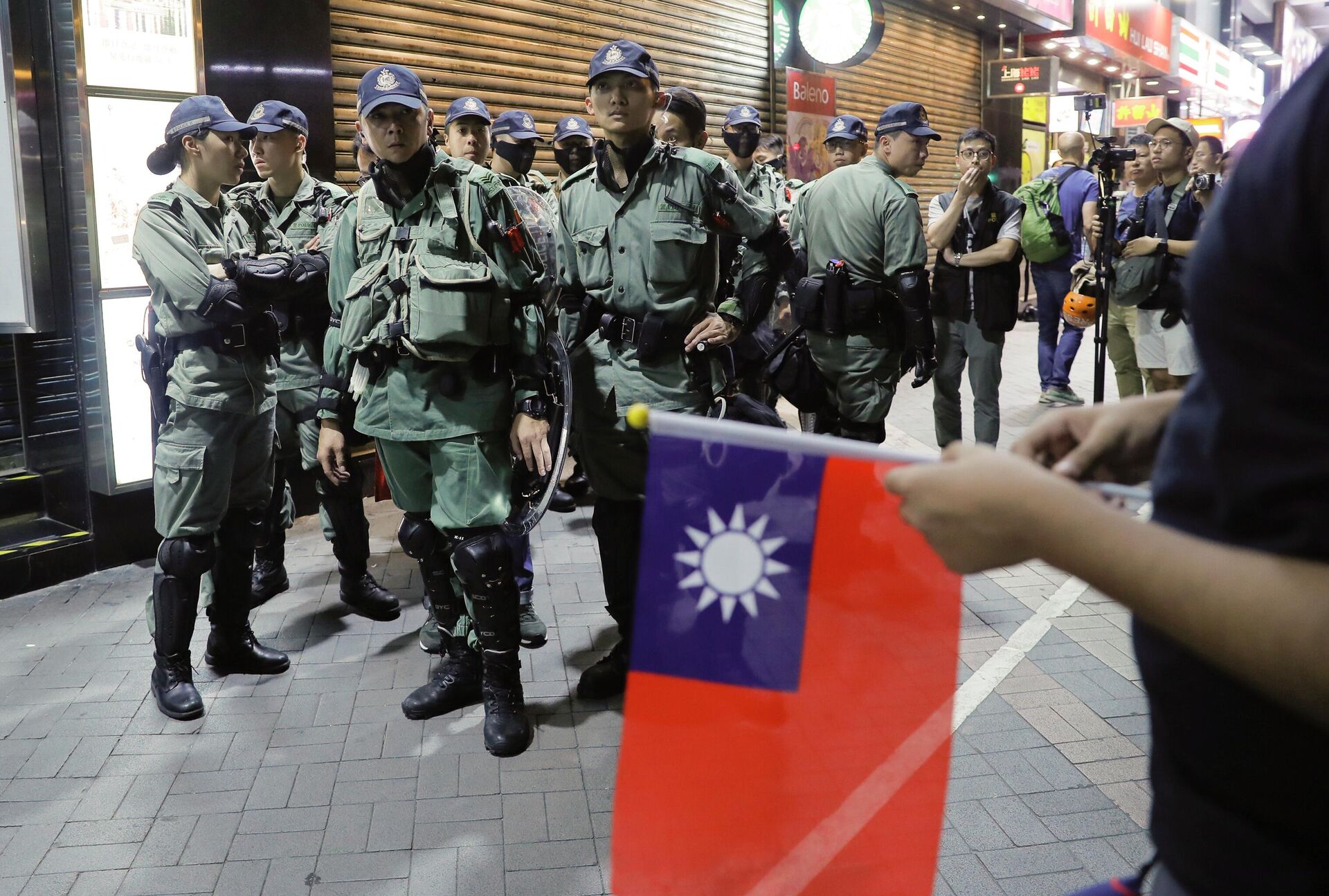 Polícia de choque olhando para pessoas segurando bandeiras de Taiwan enquanto se juntam a outras em uma manifestação para marcar o Dia Nacional de Taiwan - Sputnik Brasil, 1920, 19.09.2022