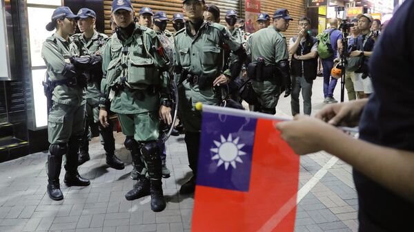 Polícia de choque olhando para pessoas segurando bandeiras de Taiwan enquanto se juntam a outras em uma manifestação para marcar o Dia Nacional de Taiwan - Sputnik Brasil