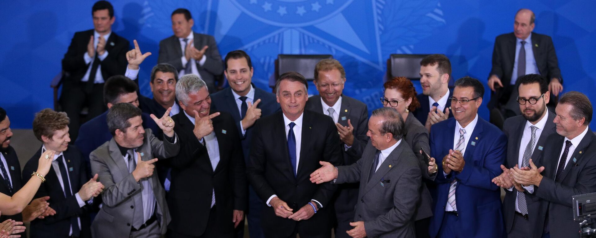 O presidente brasileiro, Jair Bolsonaro (PL), acompanhado de deputados favoráveis a projetos de flexibilização do controle de armas, durante assinatura de decreto presidencial que flexibiliza regras para colecionadores, atiradores desportivos e caçadores (CACs), em Brasília, em 7 de maio de 2019 - Sputnik Brasil, 1920, 21.06.2022