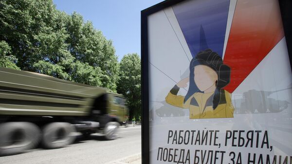 Veículo militar passa ao lado de um cartaz com a imagem do menino Alyosha em uma parada de transporte público em Nalchik, na região russa de Belgorod, 31 de maio de 2022 - Sputnik Brasil