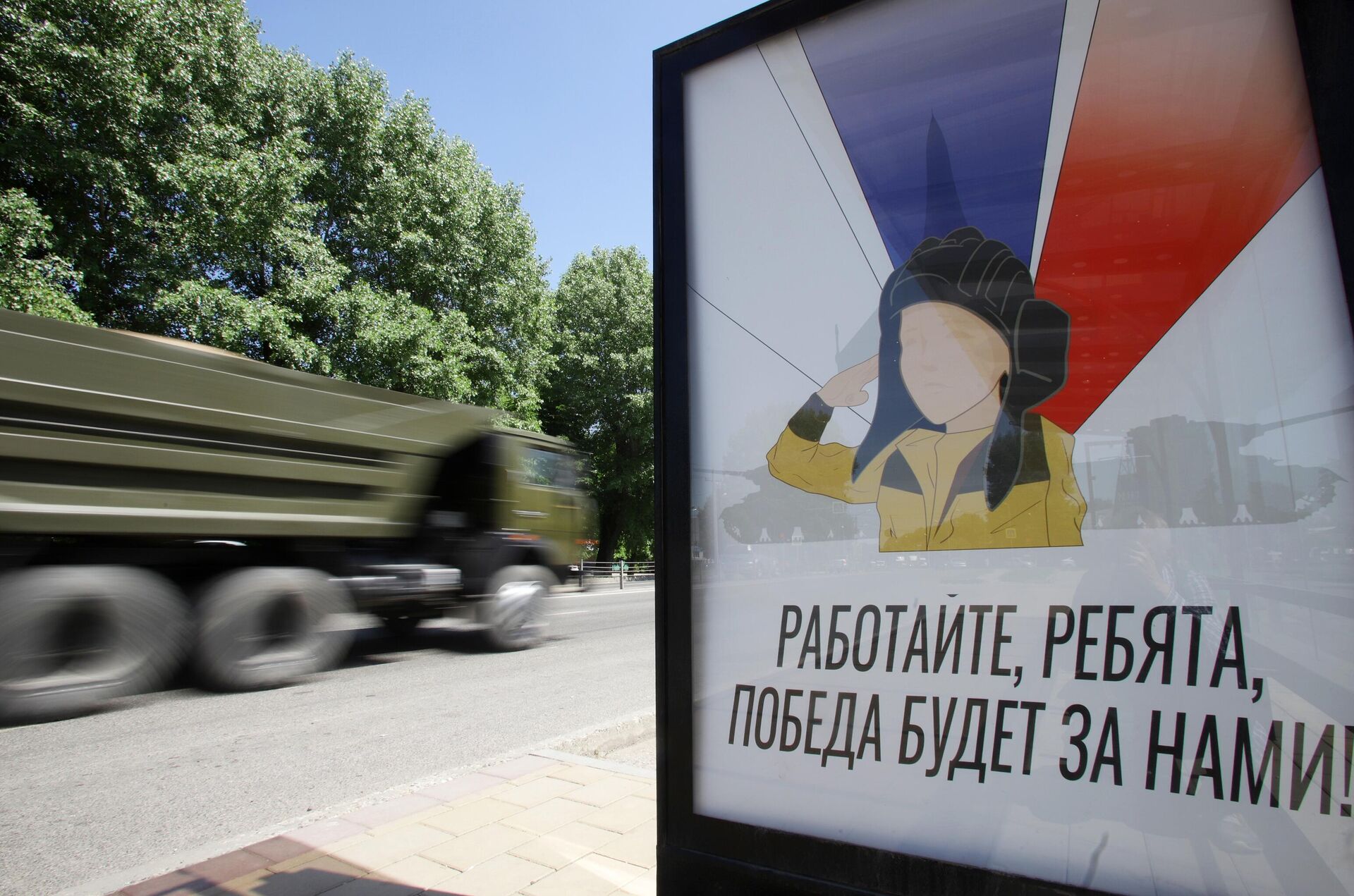 Veículo militar passa ao lado de um cartaz com a imagem do menino Alyosha em uma parada de transporte público em Nalchik, na região russa de Belgorod, 31 de maio de 2022 - Sputnik Brasil, 1920, 03.07.2022