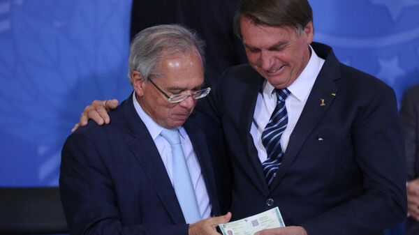 O ministro da Economia do Brasil, Paulo Guedes (à esquerda), participa, ao lado do presidente brasileiro, Jair Bolsonaro, de cerimônia de lançamento do novo passaporte do país, Brasília, 27 de junho de 2022 - Sputnik Brasil
