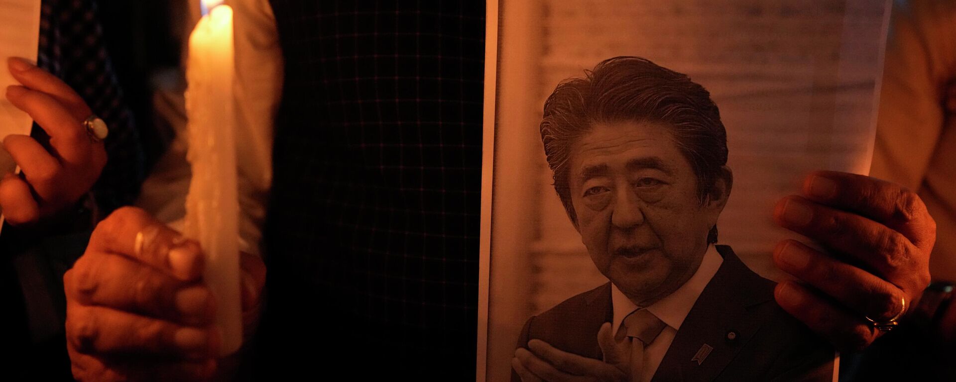 Homem segura uma vela e uma foto de Shinzo Abe durante uma reunião de oração - Sputnik Brasil, 1920, 09.07.2022