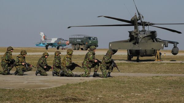 Com um jato de combate MIG 21 e um helicóptero Blackhawk ao fundo, soldados dos EUA participam de exercício militar conjunto com as Forças Armadas romenas na base aérea de Mihail Kogalniceanu, Romênia, 8 de março de 2017 - Sputnik Brasil