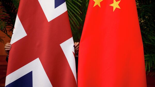 Um trabalhador arruma as bandeiras nacionais britânica e chinesa em exibição para uma cerimônia durante o 7º diálogo econômico estratégico China-Reino Unido na Diaoyutai State Guesthouse, em Pequim, 21 de setembro de 2015 - Sputnik Brasil