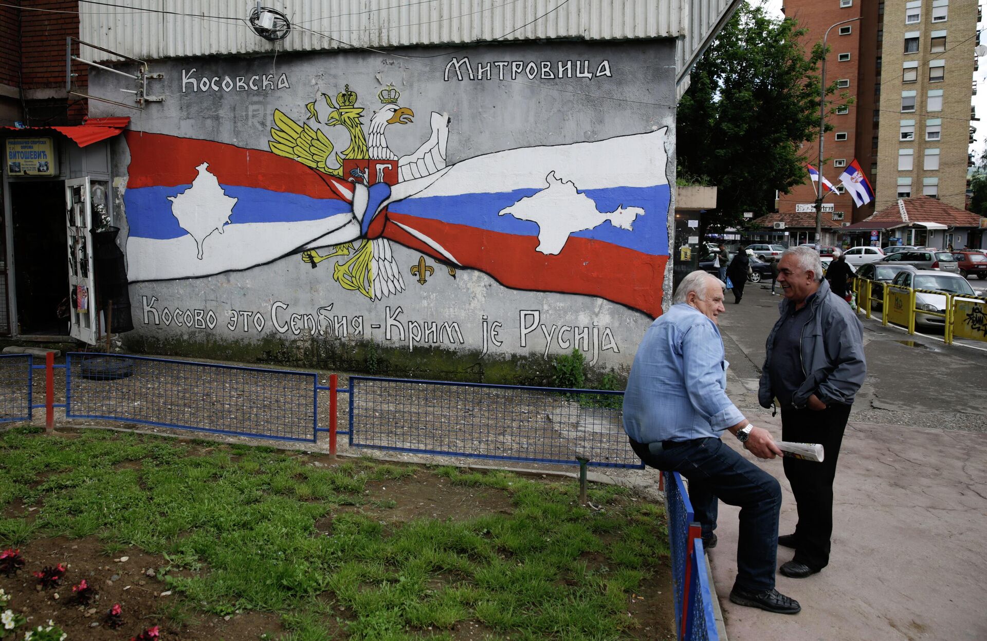 Pessoas descansam ao lado de grafite com os escritos Kosovo é Sérvia, Crimeia é Rússia, em Kosovska Mitrovica, Sérvia, 28 de maio de 2019 - Sputnik Brasil, 1920, 11.12.2022