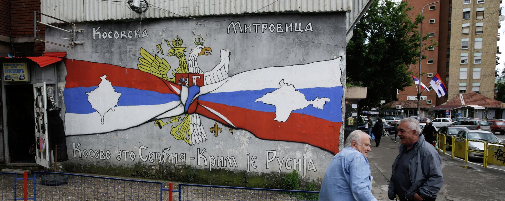 Pessoas descansam ao lado de grafite com os escritos Kosovo é Sérvia, Crimeia é Rússia, em Kosovska Mitrovica, Sérvia, 28 de maio de 2019 - Sputnik Brasil, 1920, 31.07.2022