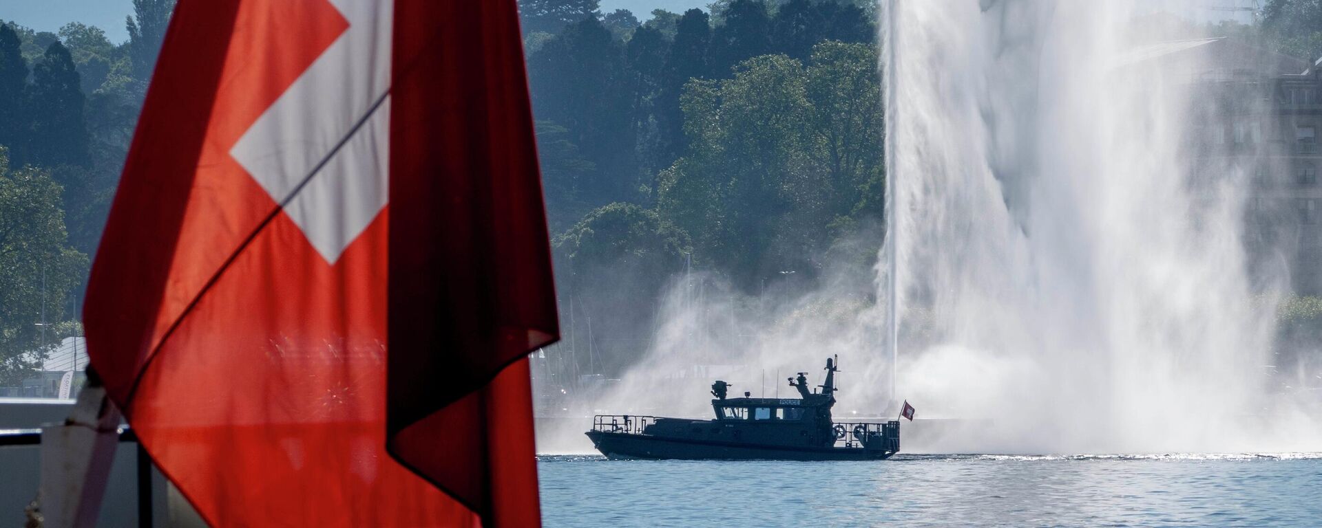Um barco da polícia passa por uma bandeira suíça e uma fonte no Lago Genebra, em Genebra, Suíça, terça-feira, 15 de junho de 2021 - Sputnik Brasil, 1920, 11.04.2023