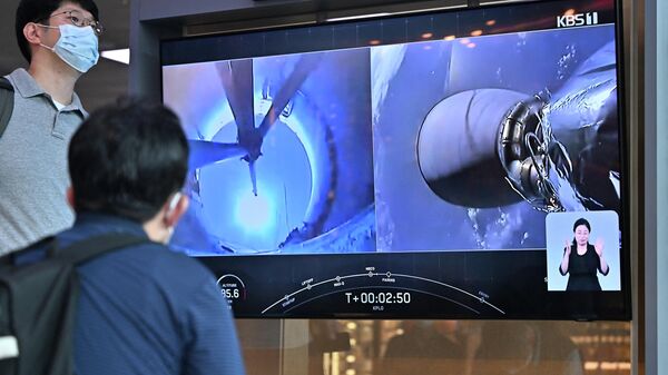 Pessoas assistem em uma estação ferroviária em Seul a filmagem ao vivo de foguete SpaceX Falcon 9 sendo lançado com o primeiro orbitador lunar da Coreia do Sul, o Danuri, em Cabo Canaveral, na Flórida, 5 de agosto de 2022 - Sputnik Brasil