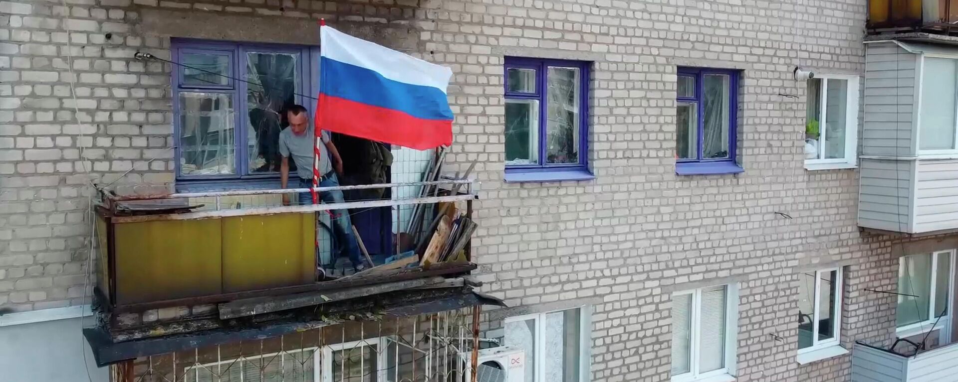 Homem coloca bandeira russa na varanda de edifício residencial em Lisichansk, na República Popular de Lugansk (RPL), em 4 de julho de 2022 - Sputnik Brasil, 1920, 28.09.2022