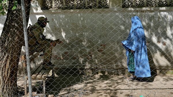 Talibã está de guarda enquanto mulher entra no escritório de passaportes do governo em Cabul, Afeganistão, 27 de abril de 2022 - Sputnik Brasil