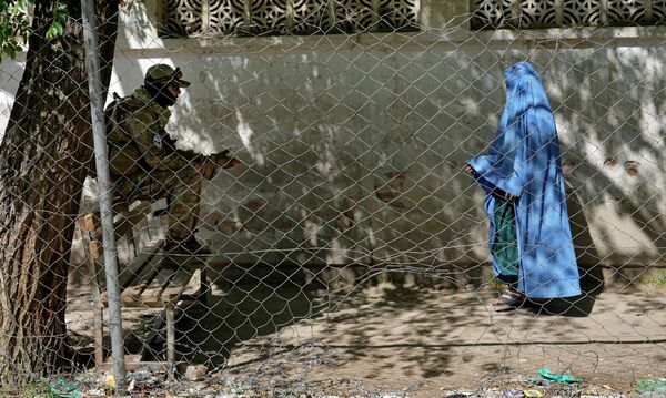 Talibã está de guarda enquanto mulher entra no escritório de passaportes do governo em Cabul, Afeganistão, 27 de abril de 2022. - Sputnik Brasil
