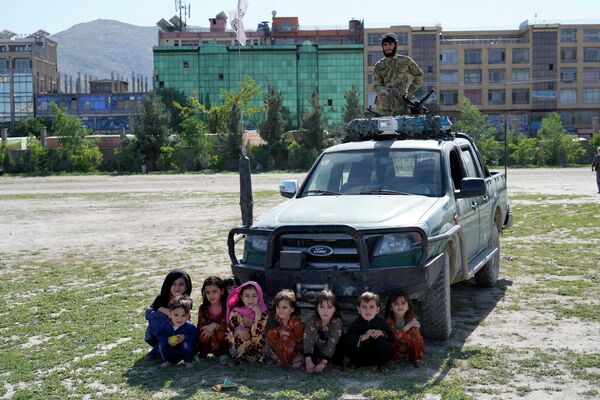 Crianças afegãs assistem a uma corrida de cavalos enquanto um talibã vigia, no parque Chaman-e-Huzori, em Cabul, Afeganistão, 6 de maio de 2022. - Sputnik Brasil