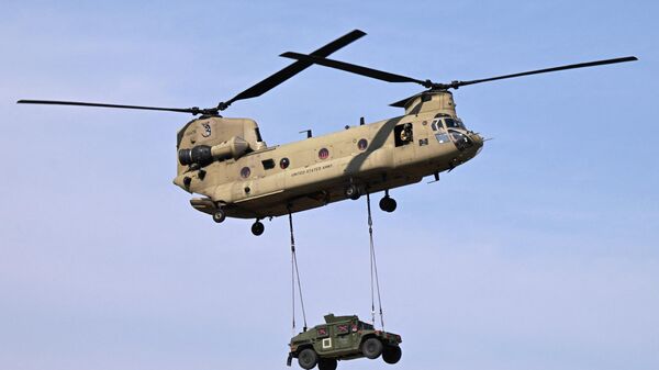 Um helicóptero Boeing CH-47F Chinook da 101ª Divisão Aerotransportada do Exército dos EUA transporta um veículo militar durante um exercício de demonstração na Base Aérea Mihail Kogalniceanu perto de Constanta, Romênia, 30 de julho de 2022 - Sputnik Brasil