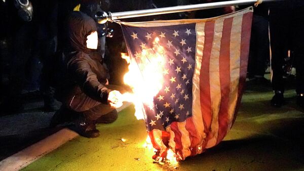 Manifestante põe fogo em bandeira americana durante protesto contra a desigualdade racial e a violência policial em Portland, Oregon, EUA, 27 de julho de 2020 (Foto de Arquivo) - Sputnik Brasil