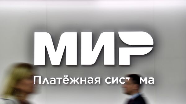 Pessoas passam em frente ao logo do sistema de pagamento russo Mir no XXV Fórum Econômico Internacional de São Petersburgo, Rússia, 16 de junho de 2022 - Sputnik Brasil