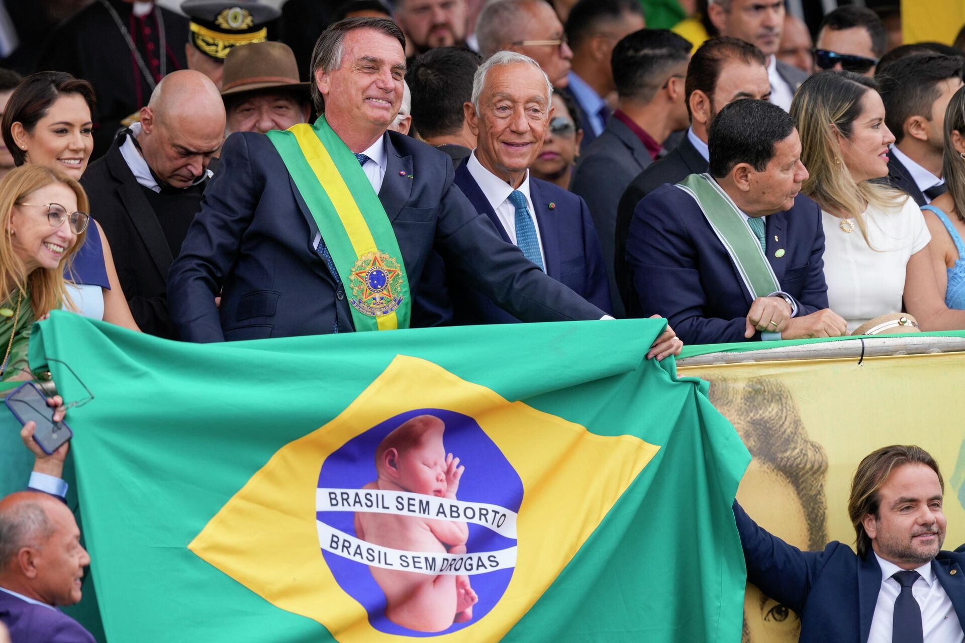 O presidente Jair Bolsonaro segura uma bandeira brasileira com texto que diz em português Brasil sem aborto. Brasil sem drogas - Sputnik Brasil, 1920, 16.12.2022