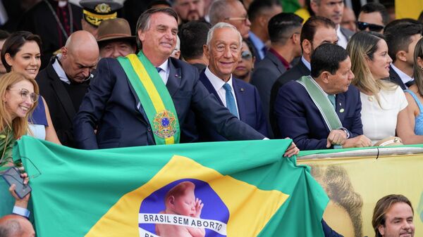 O presidente Jair Bolsonaro segura uma bandeira brasileira com texto que diz em português Brasil sem aborto. Brasil sem drogas - Sputnik Brasil