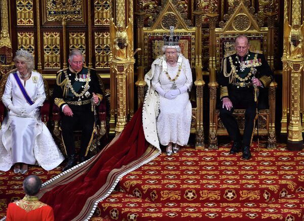 Rainha Elizabeth II, sentada no trono na Câmara dos Lordes ao lado de seu marido, príncipe Philip, à direita, e o filho, príncipe Charles com sua esposa Camilla, prepara-se para proferir o discurso durante a abertura do Parlamento no Palácio de Westminster, em Londres, 27 de maio de 2015. - Sputnik Brasil
