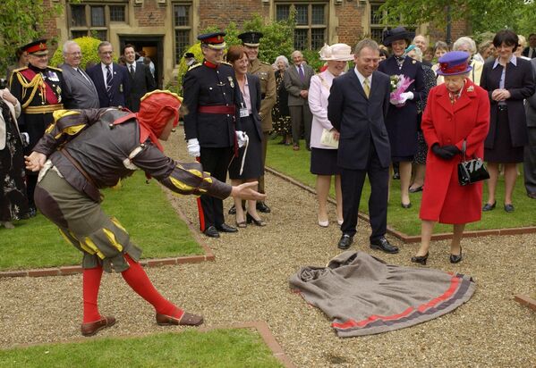 Rainha Elizabeth II é convidada a pisar em uma capa jogada a seus pés por um &quot;tolo elisabetano&quot;, conhecido como Peet Cooper, durante sua visita ao jubileu de ouro em Londres, 9 de maio de 2002. - Sputnik Brasil