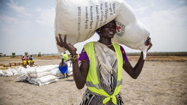 Voluntária carrega saco de grãos distribuído pelo Comitê Internacional da Cruz Vermelha (CICV) - Sputnik Brasil