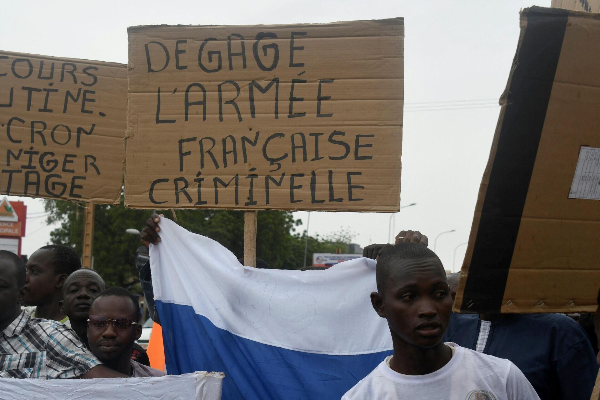 Um homem segura um cartaz que diz Limpar o exército francês criminoso enquanto pessoas se manifestam contra a presença militar francesa no Níger, em Niamey, 18 de setembro de 2022 - Sputnik Brasil, 1920, 19.09.2022