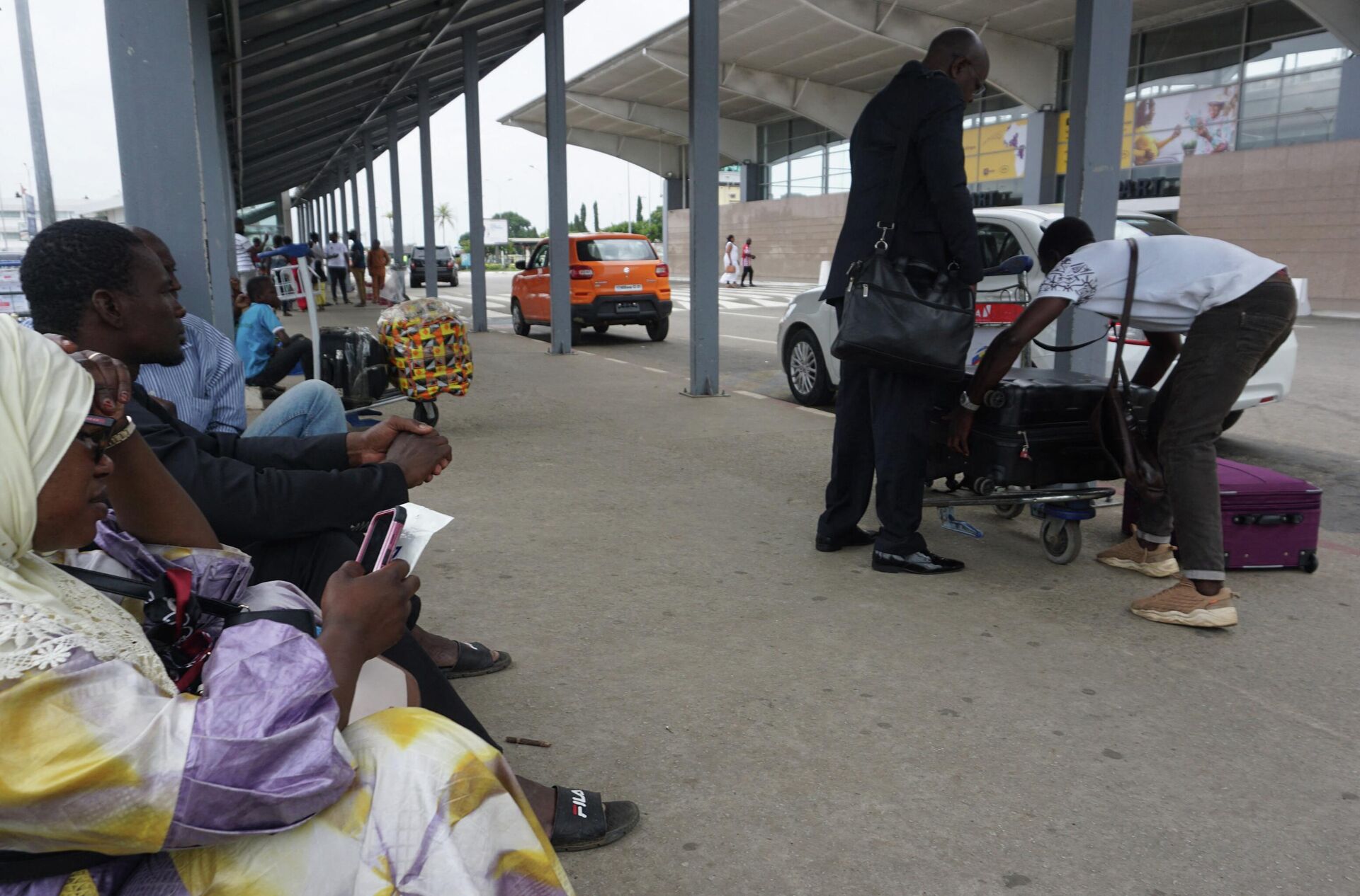 Pessoas esperam com suas bagagens fora do aeroporto internacional Felix Houphouet Boigny em Abidjan após uma greve dos controladores de tráfego aéreo, que começou na sexta-feira (23), paralisou aeroportos da África Ocidental com todos os voos comerciais cancelados, 24 de setembro de 2022 - Sputnik Brasil, 1920, 25.09.2022