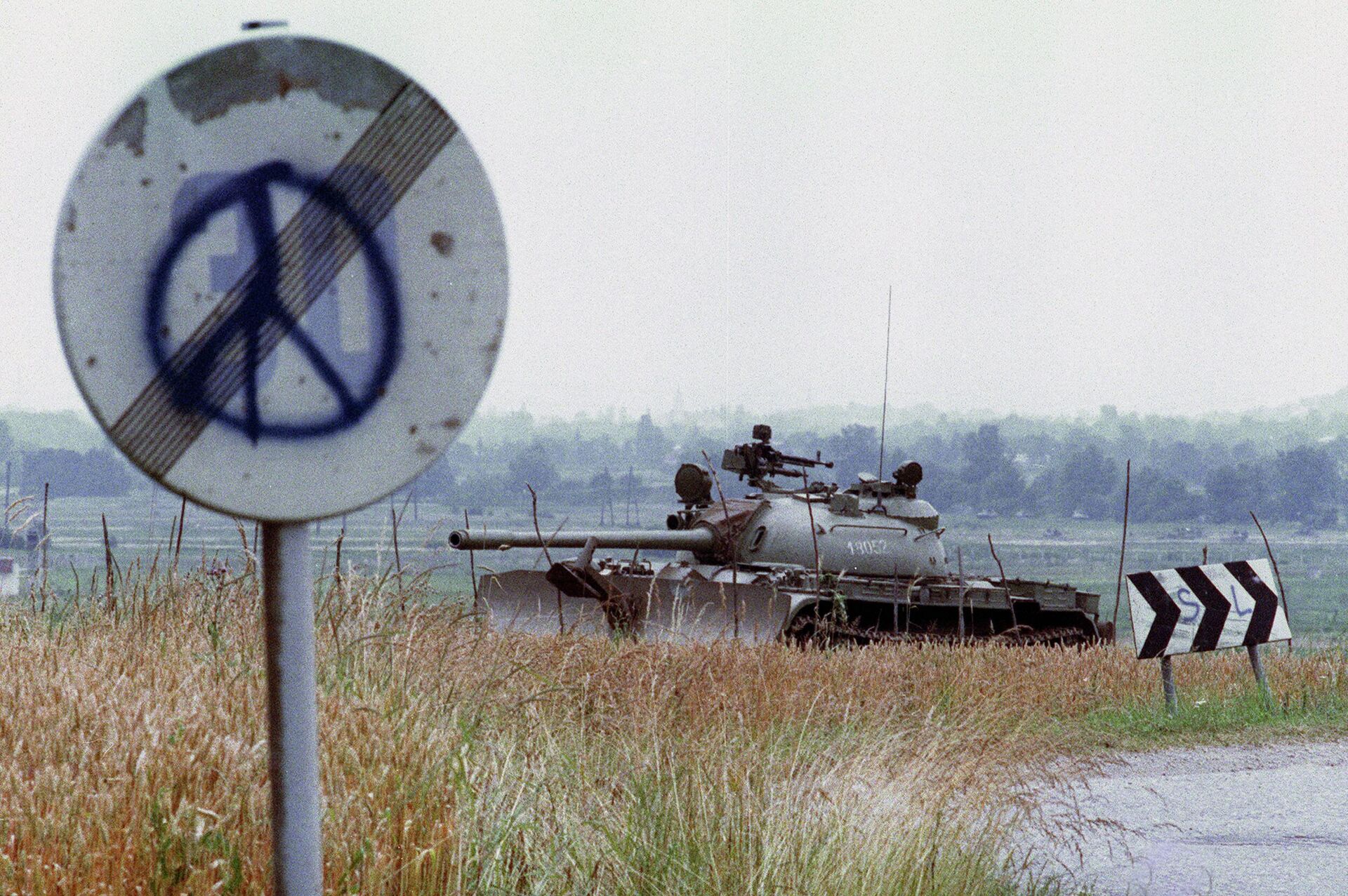 Tanque do Exército da Iugoslávia na fronteira entre a Croácia e a Eslovênia passando junto de sinal rodoviário com símbolo da paz em Jesenice, do lado esloveno, 3 de julho de 1991 - Sputnik Brasil, 1920, 30.09.2022