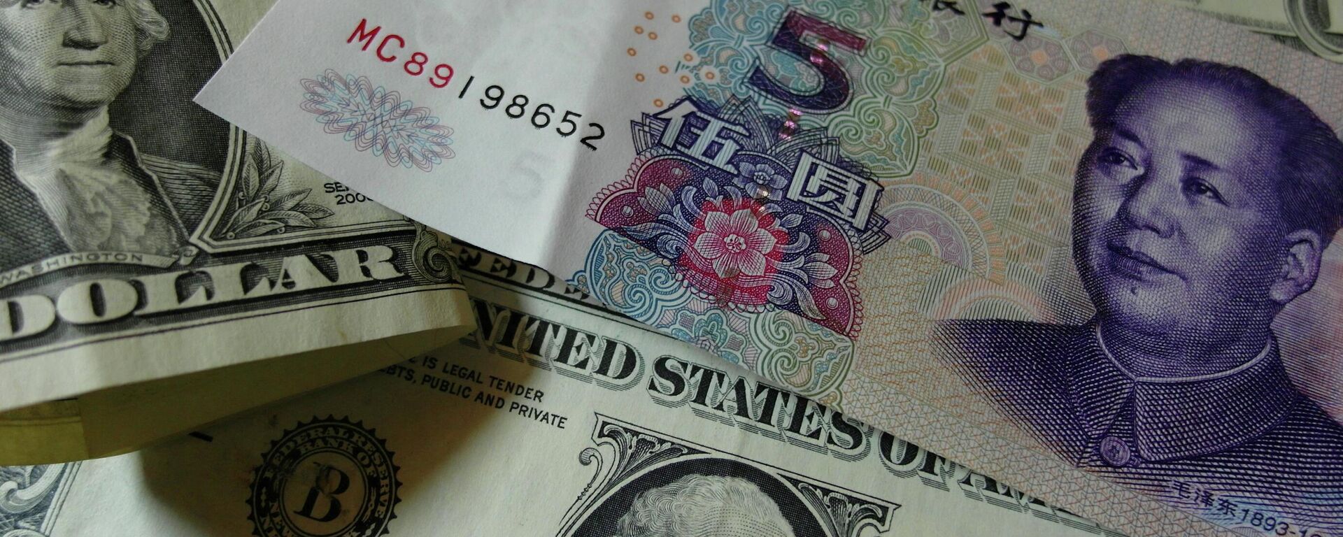 Notas de Yuan e dólares americanos são vistos em uma mesa em Yichang, província de Hubei, centro da China, 14 de agosto de 2015 - Sputnik Brasil, 1920, 01.10.2022