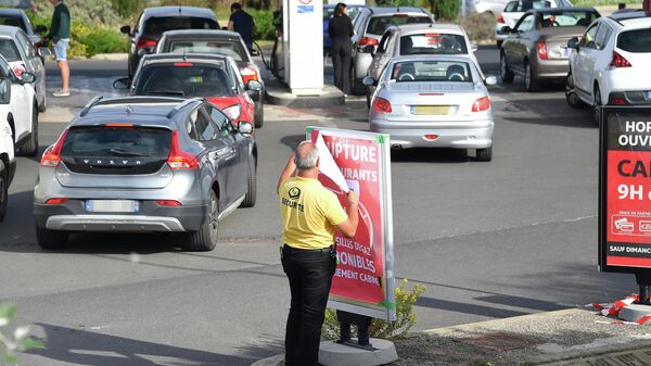 Um agente de segurança remove uma placa que diz falta de combustível enquanto motoristas fazem fila em um posto de gasolina Auchan em Perols, perto de Montpellier, no sul da França, 10 de outubro de 2022 - Sputnik Brasil