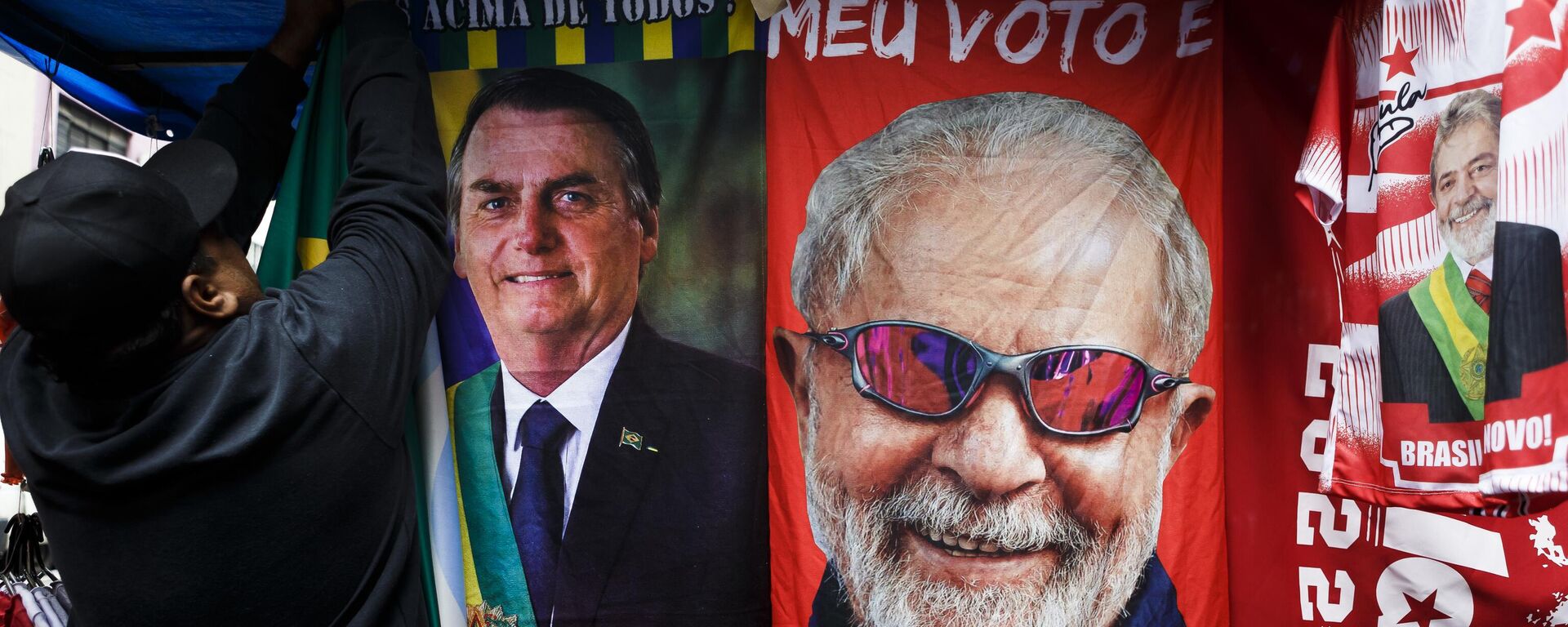 Homem pendura toalhas do presidente brasileiro, Jair Bolsonaro (PL), e do ex-presidente Luiz Inácio Lula da Silva (PT), em São Paulo, Brasil. 19 de outubro de 2022 - Sputnik Brasil, 1920, 27.10.2022