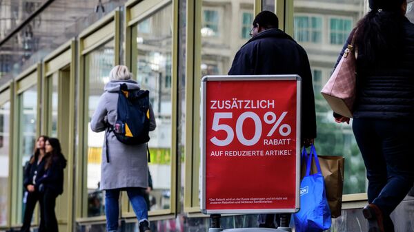 Pessoas passam por uma placa que anuncia um desconto extra de 50% em itens já com desconto do lado de fora de uma loja de varejo de roupas em Berlim, 29 de setembro de 2022 - Sputnik Brasil